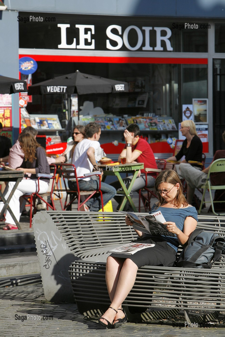 JEUNE FEMME LIT LE JOURNAL, SCENE DE RUE, BRUXELLES, BELGIQUE 