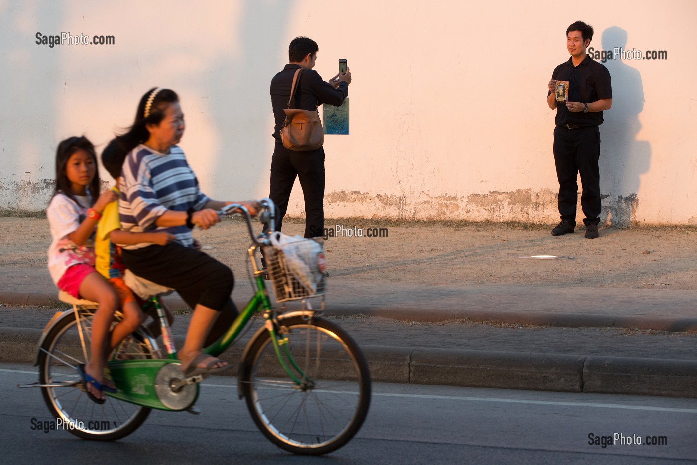 HOMME SE FAISANT PHOTOGRAPHIER DEVANT UN MUR, ET FEMME EN BICYCLETTE AVEC SES ENFANTS, BANGKOK, THAILANDE 