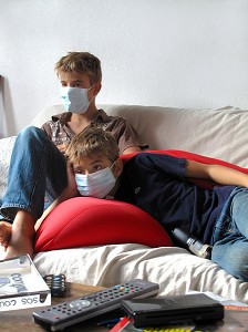 ENFANTS REGARDANT LA TELEVISION  AVEC UN MASQUE CHIRURGICAL, GESTES DE PREVENTION ET DE LUTTE CONTRE LE VIRUS H1N1 OU LA GRIPPE A 